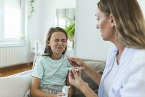 Mother is taking rapid covid-19 test at home to her sick daughter at home. Mother performing nasal swab on her child taking example to analyze if patient is positive for the infectious diseas photo