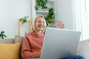 Smiling young woman using laptop at home, looking at screen, chatting, having video conference . business trainer tutoring by webcam, online training, e-coaching concept photo