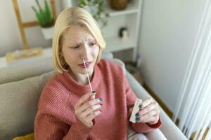 Young woman holding self testing self-administrated swab and medical tube for Coronavirus covid-19, before being self tested at home photo