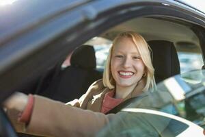 mujer joven sentada en un coche. mujer feliz conduciendo un coche y sonriendo. retrato de una feliz conductora conduciendo un coche con cinturón de seguridad. Linda señorita feliz conduciendo coche. foto