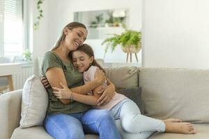 I love you so much. Portrait of happy young mother piggybacking cute smiling little daughter in living room, affectionate school age girl embracing beloved millennial female nanny or foster mom photo