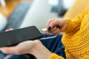 mujer manos enchufar un cargador en un inteligente teléfono. mujer utilizando teléfono inteligente con Banco de energía, cargando poder a inteligente teléfono. mujer cargando batería en móvil teléfono a hogar foto