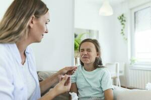 Mother is taking rapid covid-19 test at home to her sick daughter at home. Mom testing young girl for coronavirus infection taking rapid COVID-19 test photo