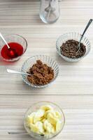 Ingredients of sundae dish as a part of non fire cooking which includes vanilla ice cream, brownie, coco powder, freshly chopped fruits and strawberry syrup. Preparation of sundae dish photo