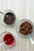 Ingredients of sundae dish as a part of non fire cooking which includes vanilla ice cream, brownie, coco powder, freshly chopped fruits and strawberry syrup. Preparation of sundae dish photo