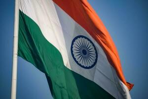 India flag flying high at Connaught Place with pride in blue sky, India flag fluttering, Indian Flag on Independence Day and Republic Day of India, tilt up shot, Waving Indian flag, Har Ghar Tiranga photo