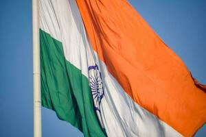 India flag flying high at Connaught Place with pride in blue sky, India flag fluttering, Indian Flag on Independence Day and Republic Day of India, tilt up shot, Waving Indian flag, Har Ghar Tiranga photo