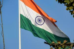 India flag flying high at Connaught Place with pride in blue sky, India flag fluttering, Indian Flag on Independence Day and Republic Day of India, tilt up shot, Waving Indian flag, Har Ghar Tiranga photo