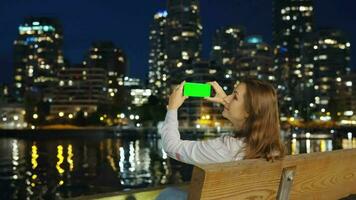 femme prend des photos de le grattes ciels de Vancouver sur sa téléphone intelligent à nuit video