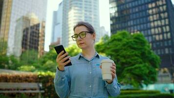 Caucasian woman in glasses walking around the city and using smartphone video