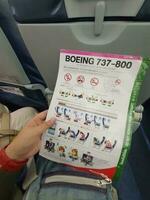 Bangkok, Thailand on May 21, 2023. A hand is holding a safety instruction sheet for a Boeing 737-800 aircraft photo