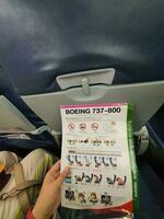 Bangkok, Thailand on May 21, 2023. A hand is holding a safety instruction sheet for a Boeing 737-800 aircraft photo