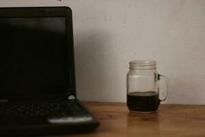 Selective focus of black coffee in glass cup on wooden table on white background. photo