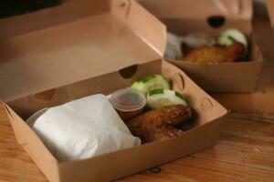 frito pollo en un caja en un de madera mesa. foto