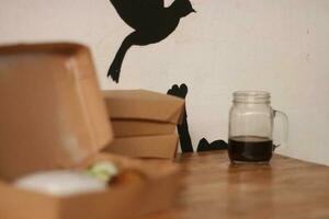 Selective focus of black coffee in glass cup on wooden table on white background. photo