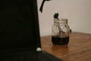 Selective focus of black coffee in glass cup on wooden table on white background. photo