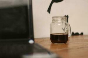 Selective focus of black coffee in glass cup on wooden table on white background. photo