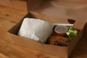 frito pollo en un caja en un de madera mesa. foto