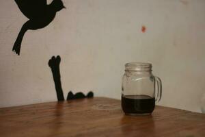 Selective focus of black coffee in glass cup on wooden table on white background. photo