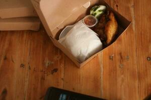 frito pollo en un caja en un de madera mesa. foto