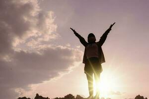 silueta fuerte mujer, ganar, éxito y vida metas concepto joven mujer con brazos arriba y mirando hacia el cielo. foto