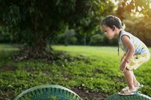 Girl enjoying walking on tire in playground alone. photo