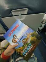 Bangkok, Thailand on May 21, 2023. A hand is holding a Lionmag magazine inside a Thai Lion Air plane photo