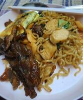 Very delicious fried noodles with toppings of sausage and vegetables and beef teriyaki. photo