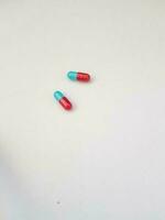 Isolated white photo of two blue and red medicine capsules.