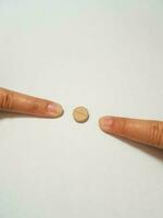 Isolated white photo of two forefingers pointing at a brown medicine tablet.