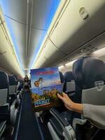 Bangkok, Thailand on May 21, 2023. A hand is holding a Lionmag magazine inside a Thai Lion Air plane photo