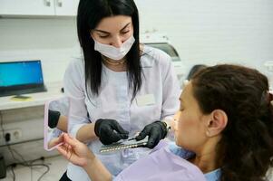 Dentist stomatologist holding dental teeth shade guide chart, choosing right enamel color for fe in dentistry clinic photo