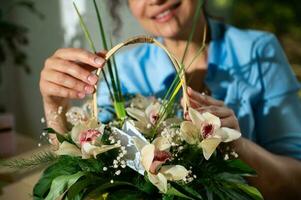 Beautiful flower arrangement in wicker basket in hands of smiling woman florist, for festive event. Happy Women's Day photo