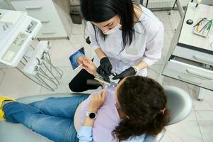 Dentist holding teeth color chart, discussing with patient the teeth prosthesis and bleaching in dental clinic. Top view photo