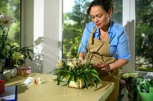 Multi-ethnic woman, inspired florist working on flower arrangement in floral design studio. Floristics. Floral shop photo