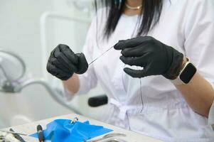 Close-up dental floss in the hands of a doctor dentist working with gypsum dental model of human jaw in medical clinic photo