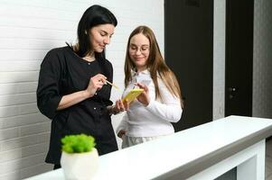 Receptionist and doctor dentist, GP or medical staff checking appointments with patients in modern medical clinic photo