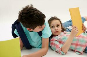 Authentic school kids, little girl and teen boy look at each other, hold textbooks and school supplies. Back to school photo