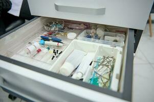 Close-up open drawer in a dentist's office with dental instruments, consumables and supplies used in a dental practice photo