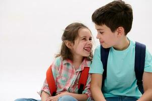 Mischievous little girl, showing tongue and making faces, smiling to her older brother, isolated over white background photo