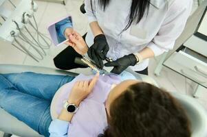 Top view female patient in dentist chair discuss the color and shade of veneers with her orthodontist. Teeth prosthesis photo