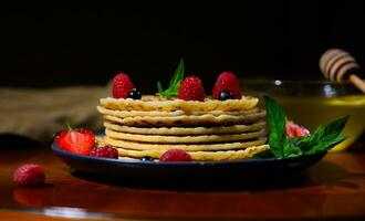 Still life with food. Plate of pancakes dripping with honey with raspberries and and mint leaves over dark background photo