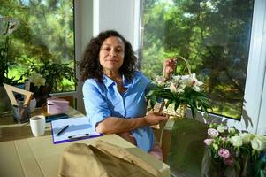 Florist entrepreneur engaged on drawing sketches with flower arrangements for festive life event in floral shop photo