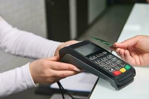 Selective focus on POS terminal, credit card reader in the hands holding it out for cashless payment view NFC technology photo