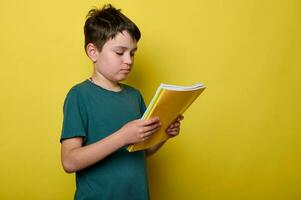 Adorable Caucasian schoolboy in green casual t-shirt, primary school student, holds colorful textbooks. Back to school. photo