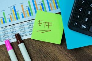 Concept of ETF write on sticky notes isolated on Wooden Table. photo