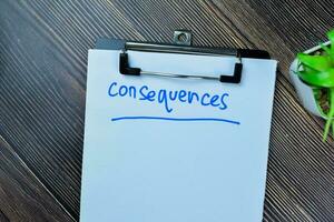 Concept of Consequences write on paperwork isolated on Wooden Table. photo