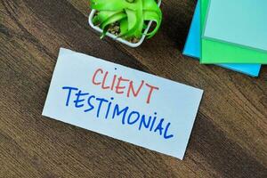 Concept of Client Testimonial write on sticky notes isolated on Wooden Table. photo