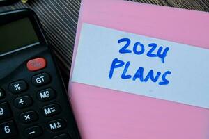 Concept of Plans 2024 write on sticky notes isolated on Wooden Table. photo