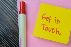 Concept of Get In Touch write on sticky notes isolated on Wooden Table. photo